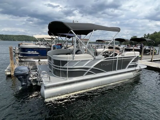 Slide: The Image of 2022 Sylvan 8520 LZ pontoon boat docked on a lake under cloudy skies. - 5