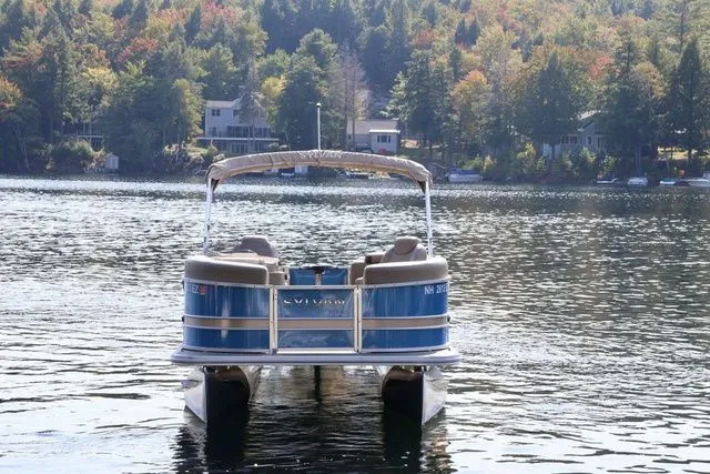 Slide: The Image of 2022 Sylvan 8520 LZ pontoon boat on a scenic lake with forested shoreline. - 2