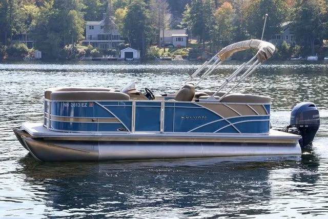 Slide: The Image of 2022 Sylvan 8520 LZ pontoon boat on a serene lake with scenic background. - 3