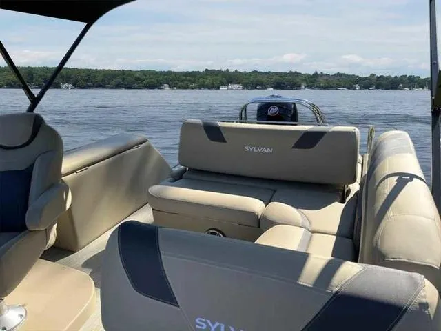 Slide: The Image of 2022 Sylvan L-3 CLZ pontoon boat interior on a serene lake. - 2