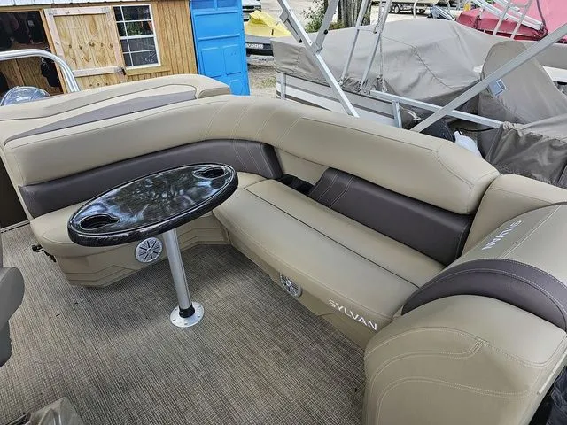 Slide: The Image of 2023 Sylvan 8522 CRS SG pontoon boat interior with beige seating and black table. - 3
