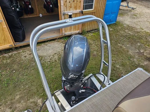 Slide: The Image of 2023 Sylvan 8522 CRS SG boat with outboard motor and ladder, parked near wooden shed. - 6