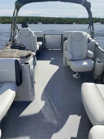 Slide: The Image of 2023 Sylvan X1 boat interior with plush seating on a sunny lake. - 2