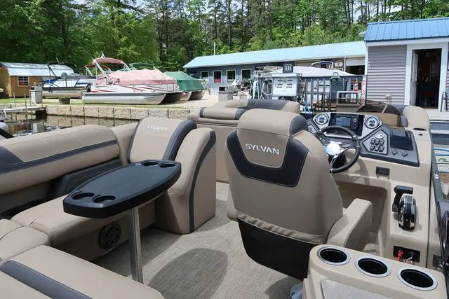 Slide: The Image of 2023 Sylvan L-3 DLZ BAR pontoon boat with luxurious seating and modern dashboard at a marina. - 19