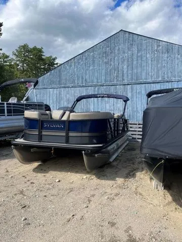 Slide: The Image of 2023 Sylvan L-3 DLZ BAR pontoon boat parked outdoors near a blue barn. - 20