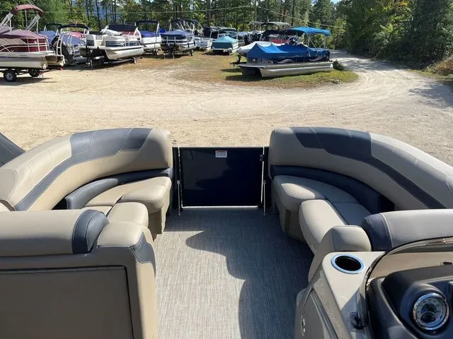 Slide: The Image of 2023 Sylvan L-3 DLZ BAR pontoon boat interior with plush seating, parked among other boats. - 23