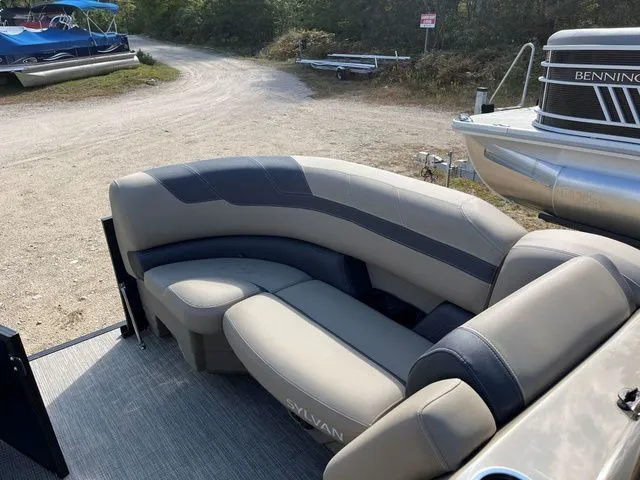 Slide: The Image of 2023 Sylvan L-3 DLZ BAR pontoon boat with beige seating, parked on a gravel path. - 28