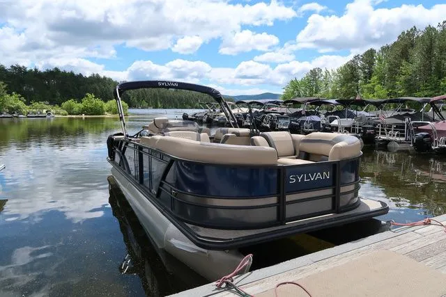Slide: The Image of 2023 Sylvan L-3 DLZ BAR pontoon boat docked on a scenic lake. - 3