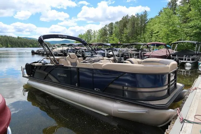 Slide: The Image of 2023 Sylvan L-3 DLZ BAR pontoon boat docked on a scenic lake. - 4