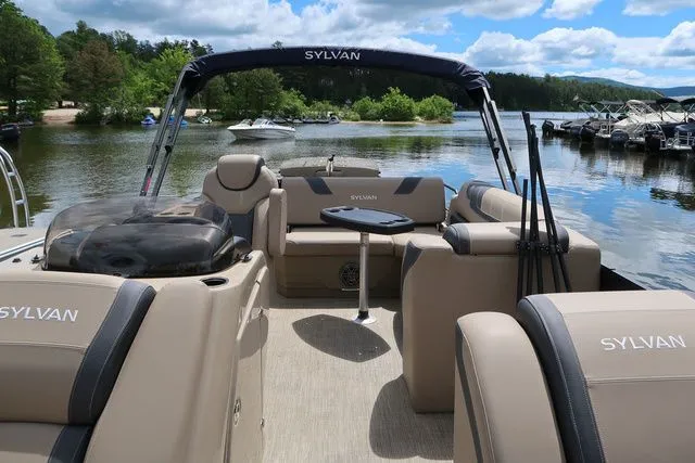 Slide: The Image of 2023 Sylvan L-3 DLZ BAR pontoon boat on a scenic lake with plush seating. - 6