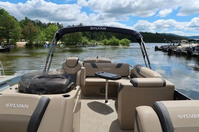 Slide: The Image of 2023 Sylvan L-3 DLZ BAR pontoon boat on a scenic lake with lush greenery. - 8