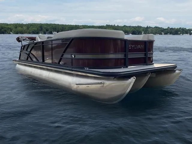 Slide: The Image of 2023 Sylvan X3 CLZ pontoon boat on a lake with scenic background. - 2