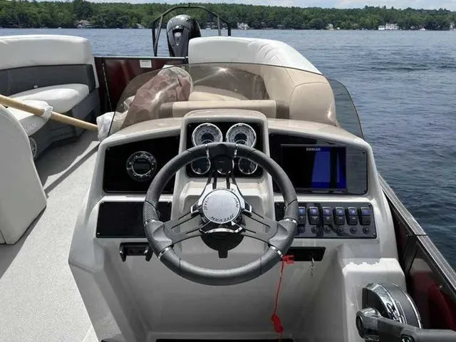 Slide: The Image of 2023 Sylvan X3 CLZ boat dashboard with steering wheel and control panel on a lake. - 9