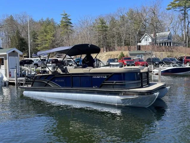 Slide: The Image of 2023 Sylvan L-5 CLZ pontoon boat docked on a calm lake. - 1