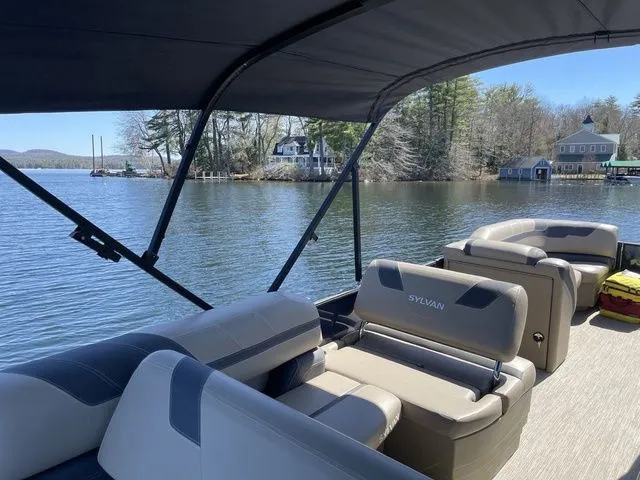 Slide: The Image of 2023 Sylvan L-5 CLZ pontoon boat on a serene lake with scenic shoreline. - 11