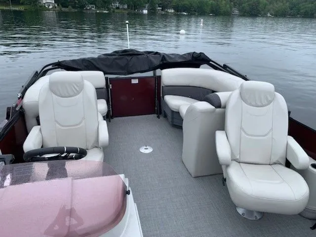 Slide: The Image of 2023 Sylvan X1 boat interior with white leather seats on a calm lake. - 6