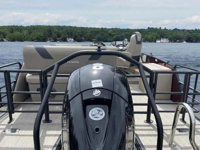 Slide: The Image of 2023 Sylvan L-1 DLZ pontoon boat on a lake, featuring a sleek outboard motor. - 9