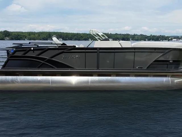 Slide: The Image of 2023 Sylvan L-5 CLZ pontoon boat on a lake, sleek design, calm water, clear sky. - 1