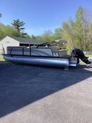 Slide: The Image of 2018 Harris 230 Sunliner Sport pontoon boat parked on pavement, surrounded by trees. - 1
