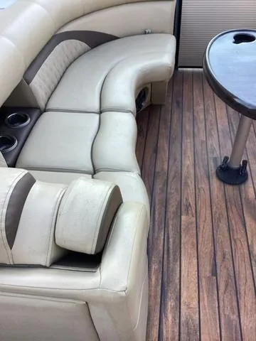 Slide: The Image of 2018 Harris 230 Sunliner Sport boat interior with beige seating and wood-style flooring. - 13