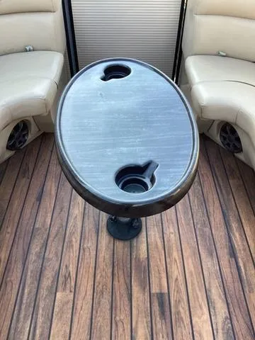 Slide: The Image of 2018 Harris 230 Sunliner Sport interior with oval table and cup holders on wood-patterned floor. - 15