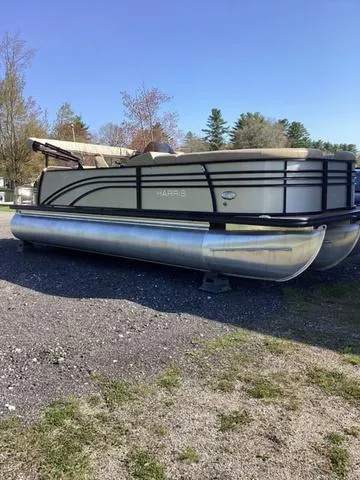 Slide: The Image of 2018 Harris 230 Sunliner Sport pontoon boat parked on gravel, surrounded by trees. - 6
