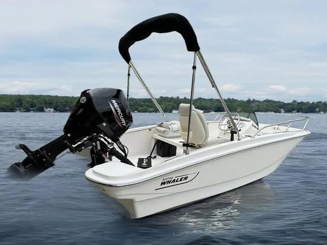 Slide: The Image of 2024 Boston Whaler 130 Super Sport boat on a lake with a Mercury outboard motor. - 1
