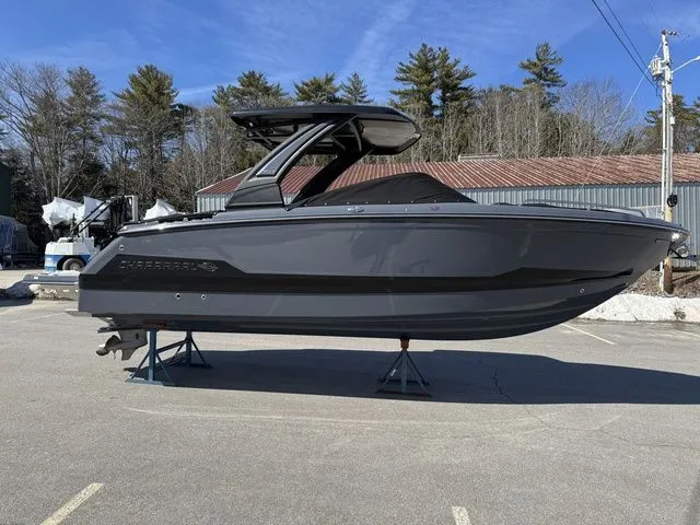 Slide: The Image of 2025 Chaparral 2870 SSX boat on stands, gray exterior, parked outdoors. - 2
