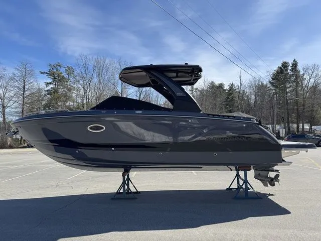 Slide: The Image of 2025 Chaparral 2870 SSX boat on stands, sleek design, parked outdoors under clear sky. - 6