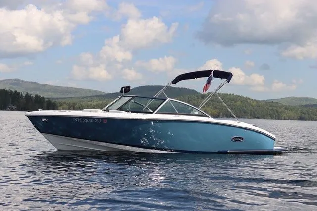 Slide: The Image of 2023 Cobalt CS22 boat on a serene lake with scenic mountain backdrop. - 1