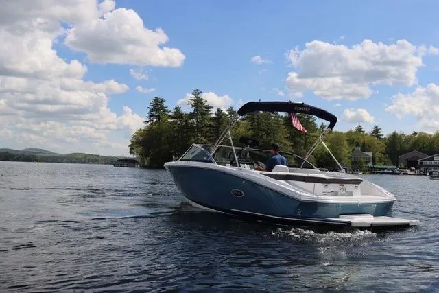 Slide: The Image of 2023 Cobalt CS22 boat cruising on a scenic lake under a partly cloudy sky. - 11