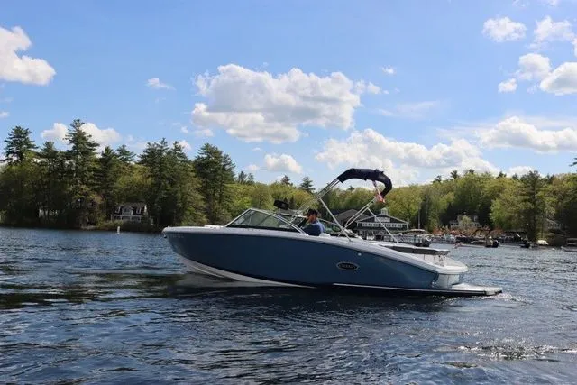 Slide: The Image of 2023 Cobalt CS22 boat cruising on a scenic lake under a clear blue sky. - 12
