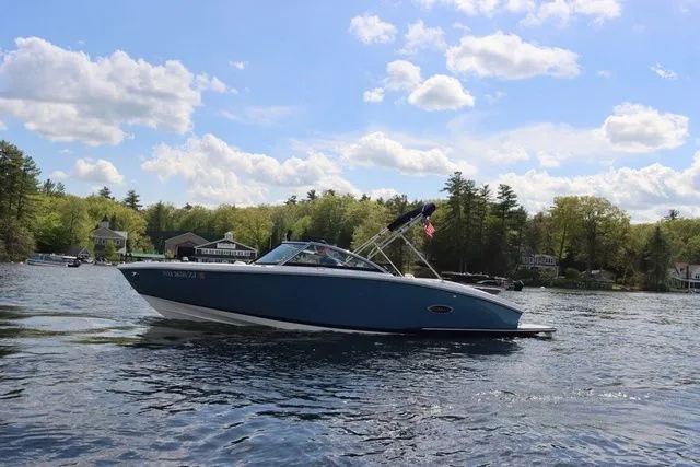 Slide: The Image of 2023 Cobalt CS22 boat cruising on a scenic lake under a partly cloudy sky. - 14