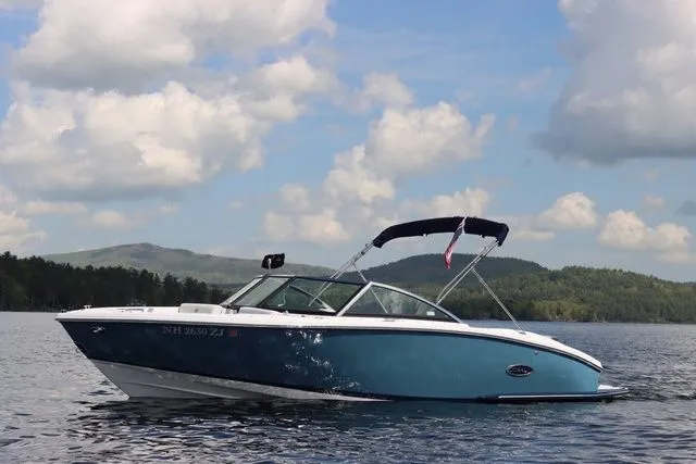 Slide: The Image of 2023 Cobalt CS22 boat on a serene lake with scenic hills and cloudy sky. - 2