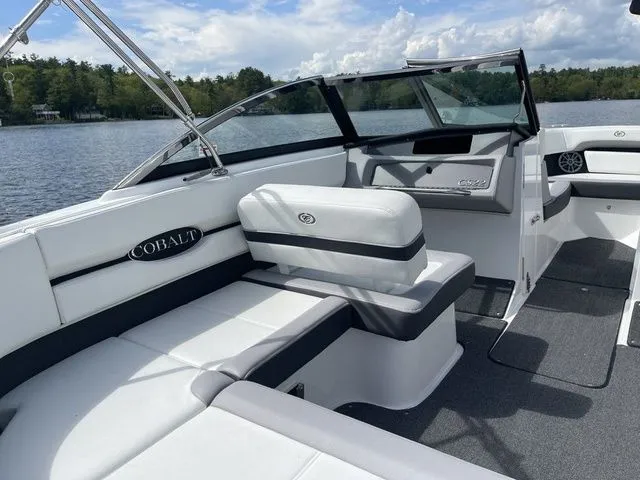 Slide: The Image of 2023 Cobalt CS22 boat interior with white seating, on a lake under a blue sky. - 23