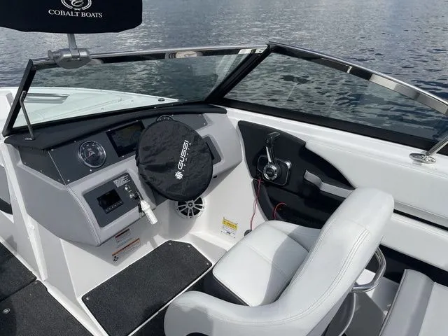 Slide: The Image of 2023 Cobalt CS22 boat cockpit with steering wheel and controls, on calm water. - 27