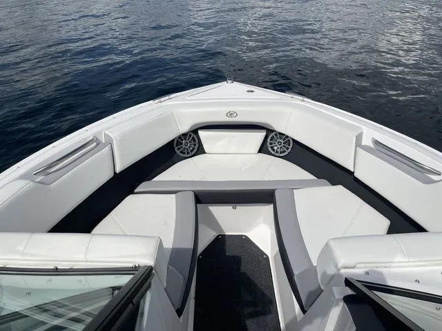 Slide: The Image of 2023 Cobalt CS22 boat interior with white seating and speakers on a calm lake. - 32