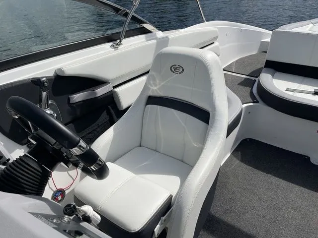 Slide: The Image of 2023 Cobalt CS22 boat interior with white seating and steering wheel, on calm water. - 35