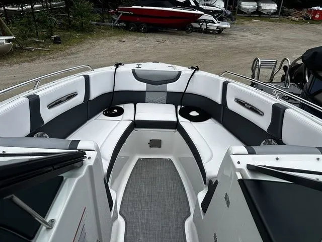Slide: The Image of 2019 Chaparral 277SX boat interior with white and gray seating, docked outdoors. - 23