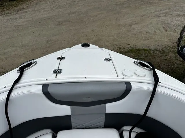 Slide: The Image of 2019 Chaparral 277SX boat bow with white and gray seating, docked on gravel. - 26