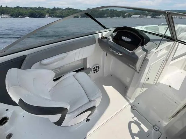 Slide: The Image of 2021 Chaparral 21 SSI Sport boat interior with sleek seating and steering, on a calm lake. - 12