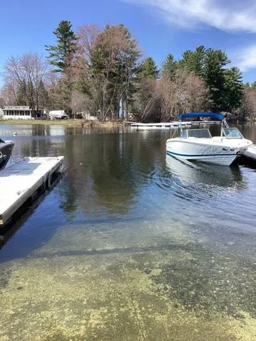 Slide: The Image of Boat docked on a serene lake with trees in the background, featuring a 2016 Cobalt 200S. - 16