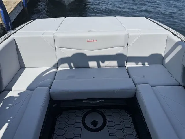 Slide: The Image of 2024 MasterCraft NXT23 boat interior with white seating, docked on water. - 11