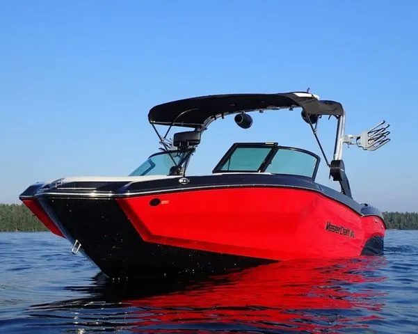 Slide: The Image of 2024 MasterCraft NXT23 boat on water, vibrant red hull, clear blue sky. - 2