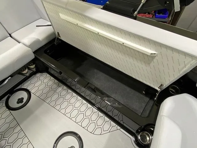 Slide: The Image of 2024 MasterCraft NXT23 boat interior with open storage compartment and hexagonal patterned flooring. - 24