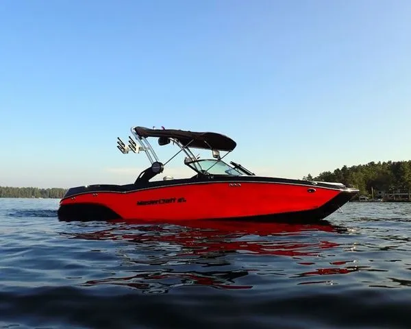 Slide: The Image of 2024 MasterCraft NXT23 boat on calm lake with clear sky. - 3