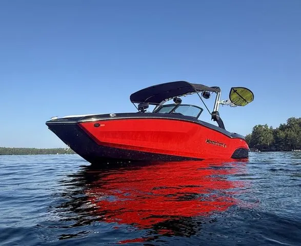 Slide: The Image of 2024 MasterCraft NXT23 boat in vibrant red on a calm lake. - 4
