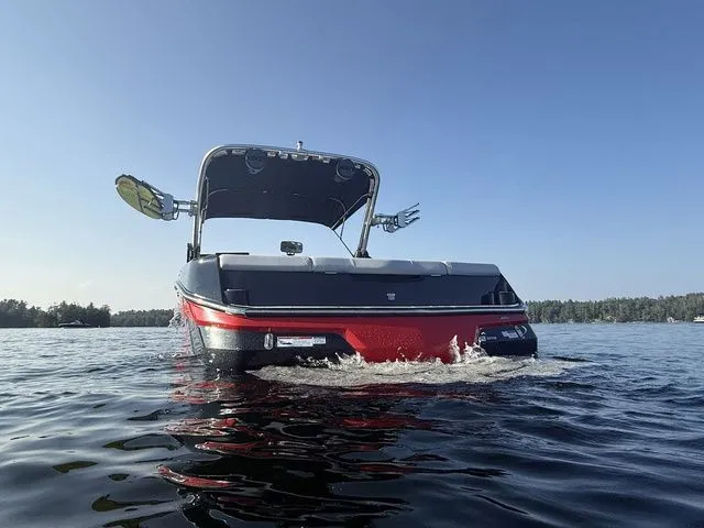 Slide: The Image of 2024 MasterCraft NXT23 boat on water, rear view, sunny day, wakeboard racks visible. - 8
