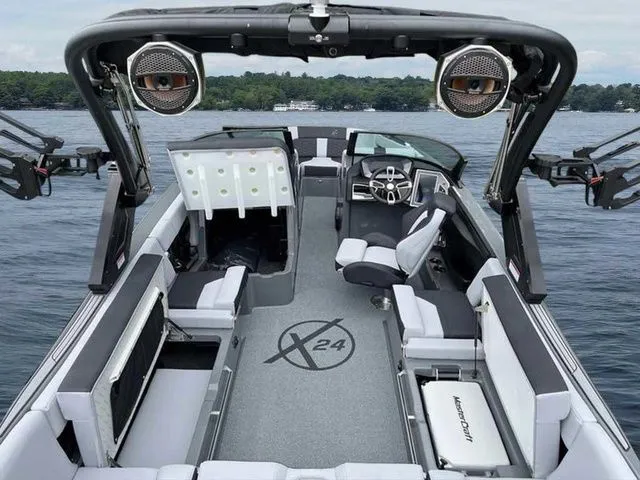 Slide: The Image of 2024 MasterCraft X24 boat interior with modern seating and advanced audio system on a lake. - 11