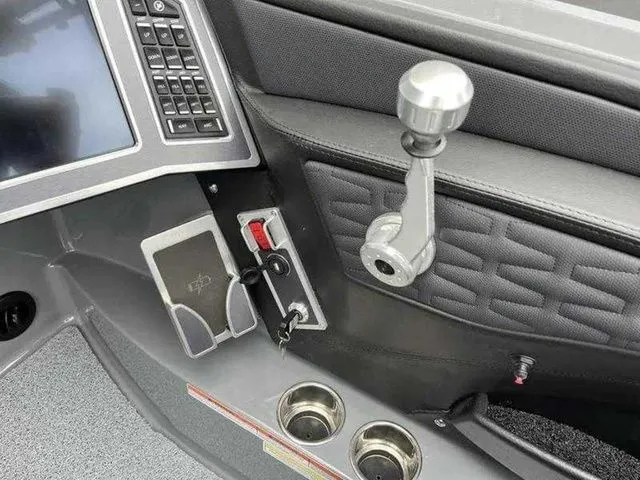 Slide: The Image of 2024 MasterCraft X24 boat dashboard with control lever, touchscreen, and cup holders. - 14